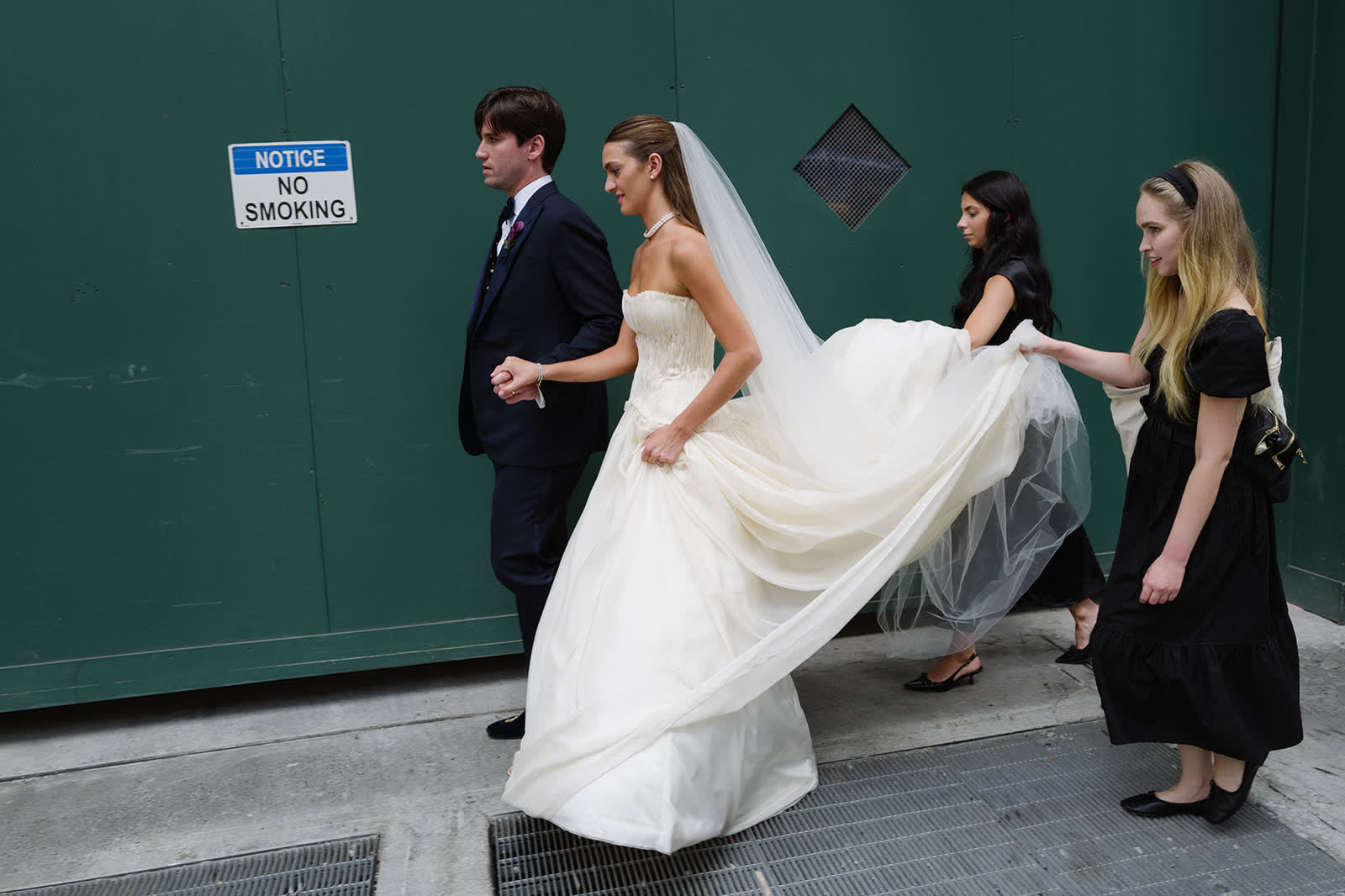 Couple walking with bridesmaids carrying the train